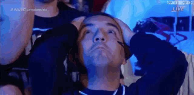 a man is holding his head in pain while watching a wrestling match .
