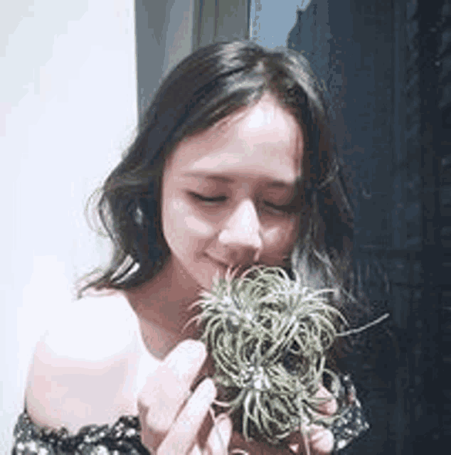 a young woman is holding a small plant in her hands .