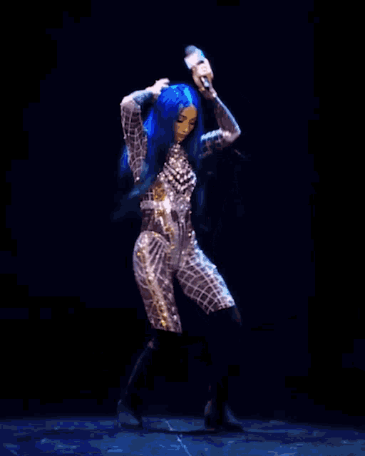 a woman with blue hair is holding a microphone while dancing