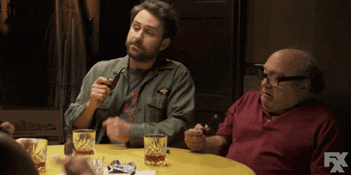 two men are sitting at a table with glasses of whiskey and a fx logo in the corner