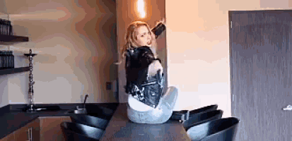 a woman in a leather jacket is sitting on a bar .