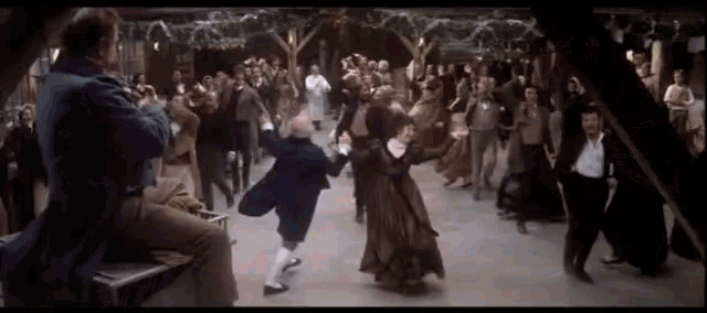 a group of people are dancing in a room in a movie .