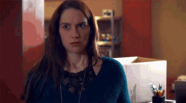 a woman in a blue sweater is making a funny face in a room .