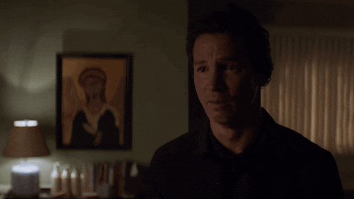 a man stands in front of a painting of an angel on a wall