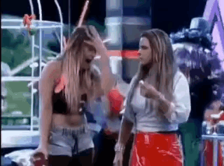 two women are standing next to each other on a stage and one is holding her hand to her head .