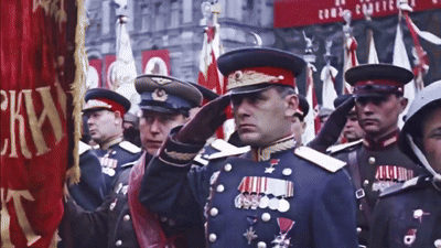 a group of men in military uniforms salute in front of a flag that says ckn