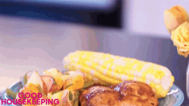 a plate of food with corn on the cob and potatoes says good housekeeping