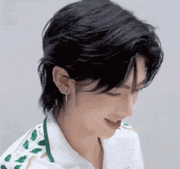 a close up of a person 's face with a mullet hairstyle and earrings .