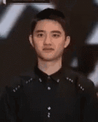 a young man in a black shirt is standing in front of a crowd .