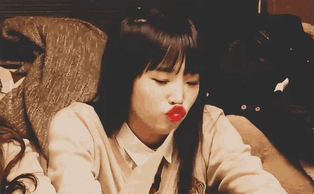 a girl with red lips is sitting on a chair
