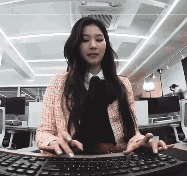 a woman in a pink jacket is typing on a black keyboard