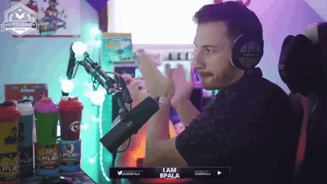 a man wearing headphones stands in front of a microphone with the name bpala on the screen