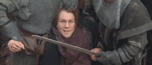 a man in a purple scarf is holding a large sword