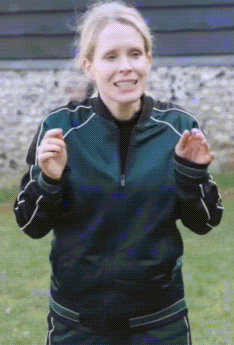 a woman wearing a green jacket and black pants is clapping