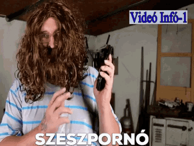 a man with a beard is holding a cell phone in front of a sign that says video info 1