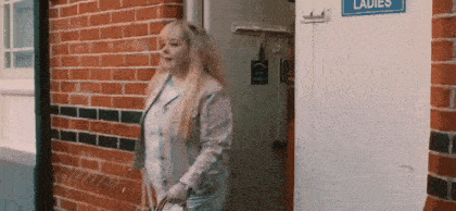 a woman stands in front of a ladies room