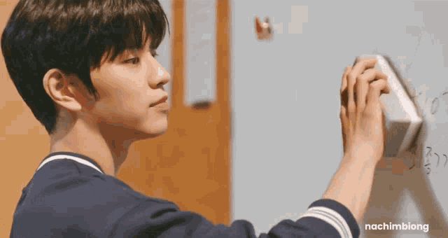 a young man is writing on a whiteboard with a sponge