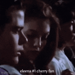 a group of people are sitting in a dark room and one of them says eleena # 1 cherry fan .