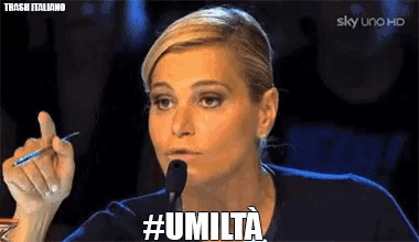 a woman speaking into a microphone with the hashtag #umilta on the screen