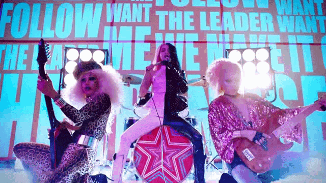 a group of drag queens are performing in front of a sign that says follow want the leader
