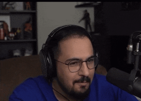 a man wearing headphones and glasses talking into a microphone .