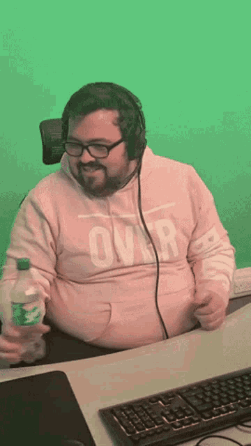 a man wearing headphones and a pink sweatshirt with the word over on it