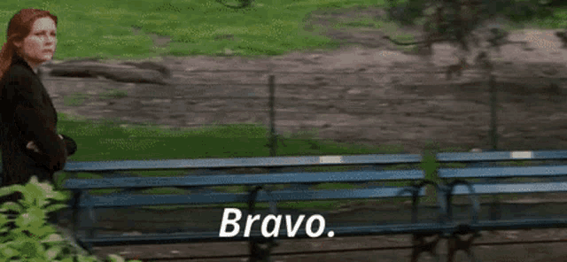 a man and a woman are standing in front of a park bench and the man says bravo