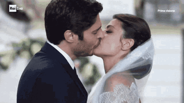 a bride and groom kiss in front of a rai 1 hd sign