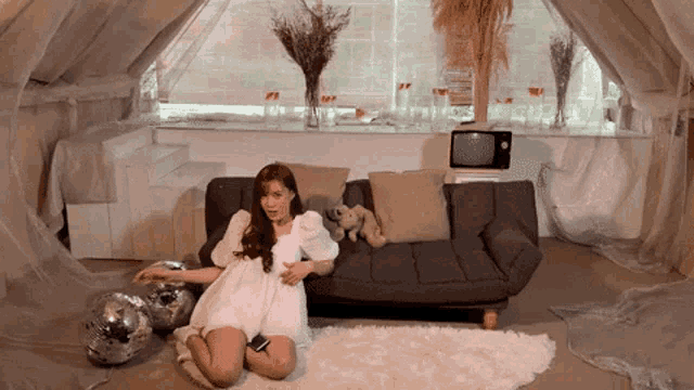 a woman in a white dress is sitting on a couch