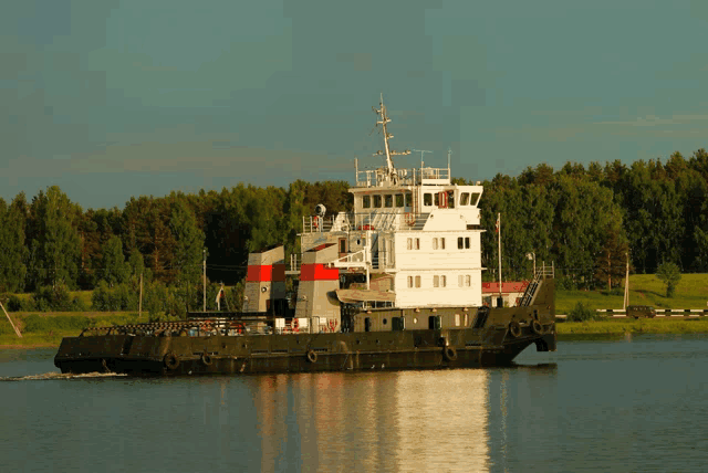 a large ship is floating on the water with trees in the background