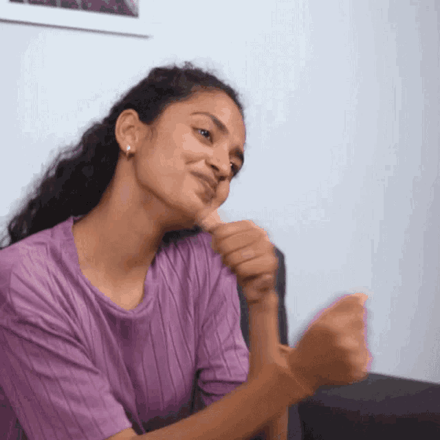 a woman in a purple shirt is smiling and clapping