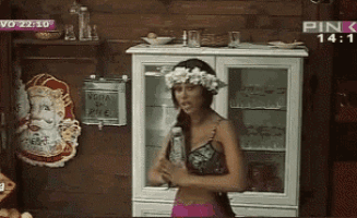a woman with a flower crown on her head is standing in front of a cabinet on a pink tv channel
