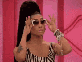 a woman wearing a zebra print dress and sunglasses is making a peace sign .
