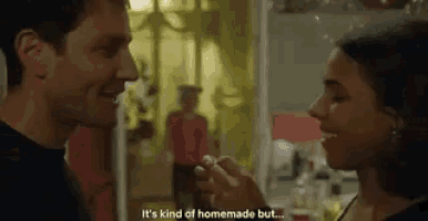 a man is putting a ring on a woman 's finger in a kitchen .