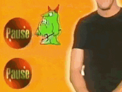 a man in a black shirt is standing in front of a pause button and a green monster .