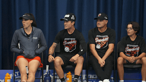 a man is kneeling down in front of a group of people wearing san francisco shirts