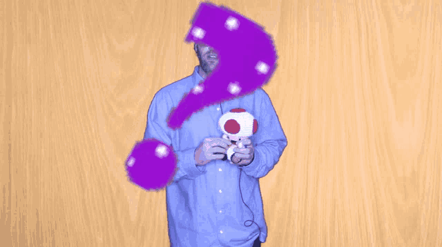 a man in a blue shirt is holding a stuffed mushroom and a purple object