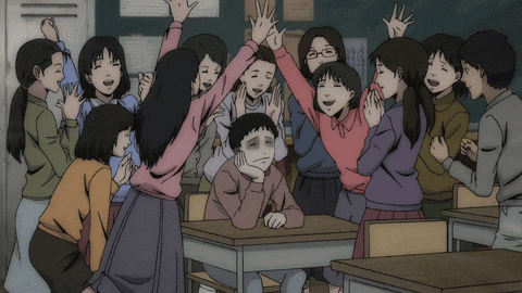 a group of children are posing for a picture with a boy sitting at a desk