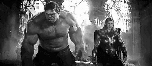 a black and white photo of the hulk and thor standing next to each other .