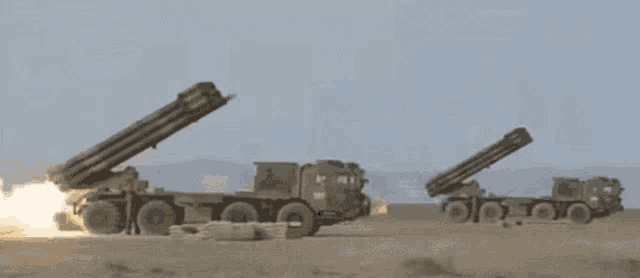 a couple of military vehicles are shooting missiles in the desert .