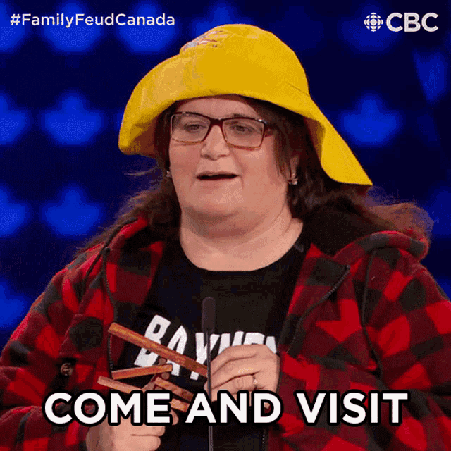 a woman wearing a plaid jacket and a yellow hat is holding sausages and says come and visit