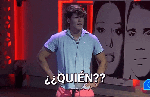 a man in a blue shirt is standing in front of a wall with a picture of a woman and the word quien on it