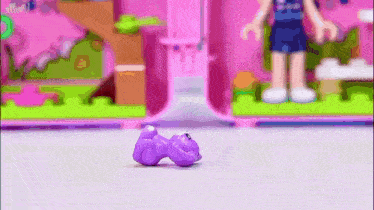 a purple toy is laying on the floor next to a doll .