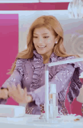 a woman wearing a purple ruffled shirt is standing in front of a mirror