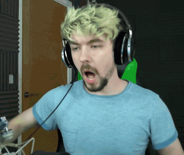 a man wearing headphones and a blue shirt is making a funny face