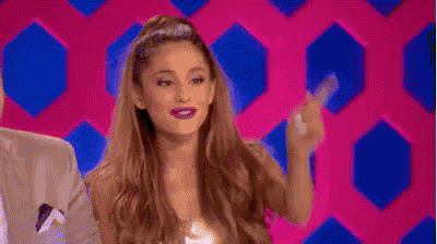 ariana grande is giving the middle finger to the camera while standing in front of a pink background .