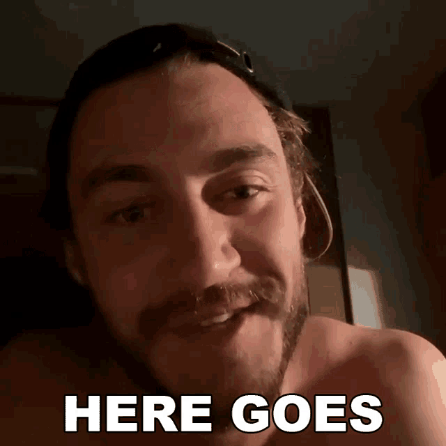 a shirtless man with a beard is smiling with the words here goes below him