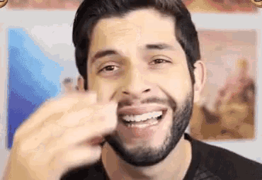 a man with a beard is smiling while holding a piece of paper in his hand .