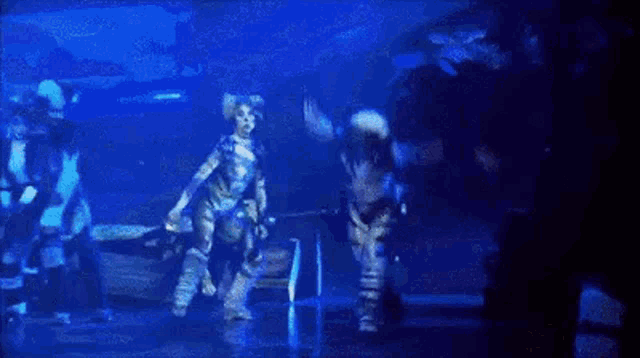 a man is doing a handstand on a stage while a group of people are standing behind him .