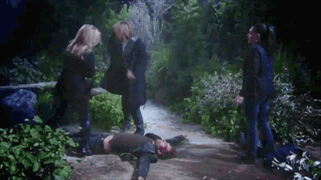 a group of people standing around a man who is laying on the ground